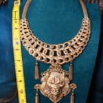 A large gold necklace with tassels and a lion head.