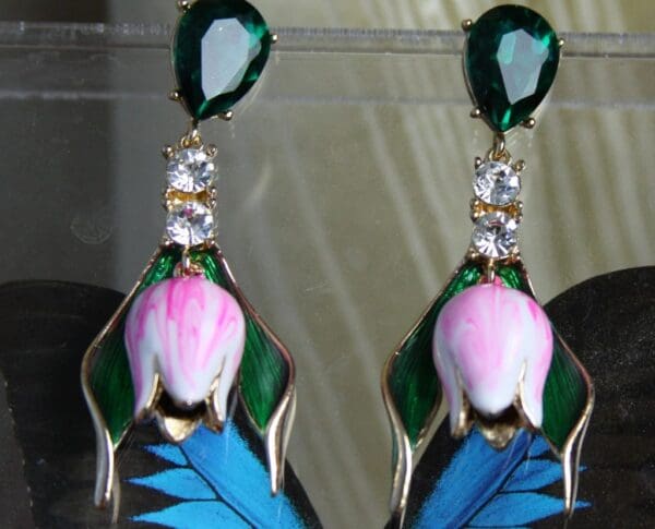 A pair of earrings with blue and pink feathers.