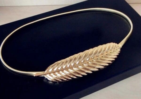 A gold leaf necklace in the shape of a fern.