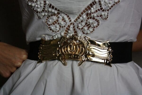 A woman wearing a white dress with a gold belt.