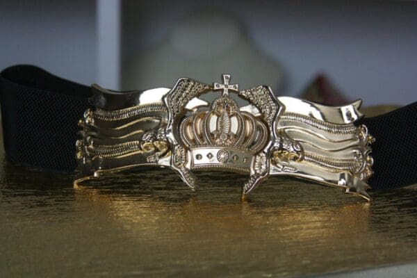 A close up of the crown on a gold bracelet