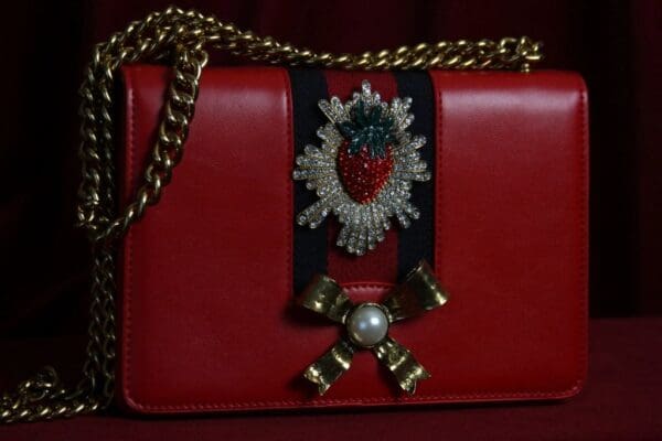 A red purse with a strawberry on it.
