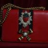 A red purse with a bow and strawberry on it.