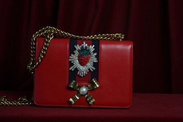 A red purse with a bow and ribbon on it.