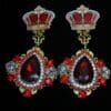 A pair of earrings with red and white stones.