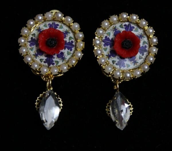 A pair of earrings with red flowers and white pearls.