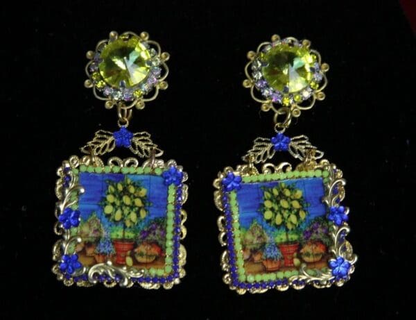 A pair of earrings with blue and green designs.