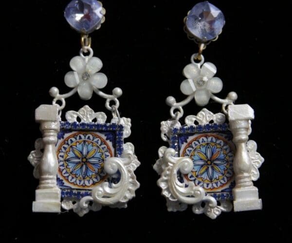 A pair of earrings with a clock and flowers.
