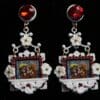 A pair of earrings with red stones and white flowers.