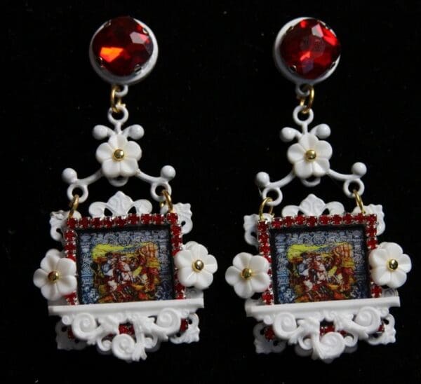 A pair of earrings with red stones and white flowers.