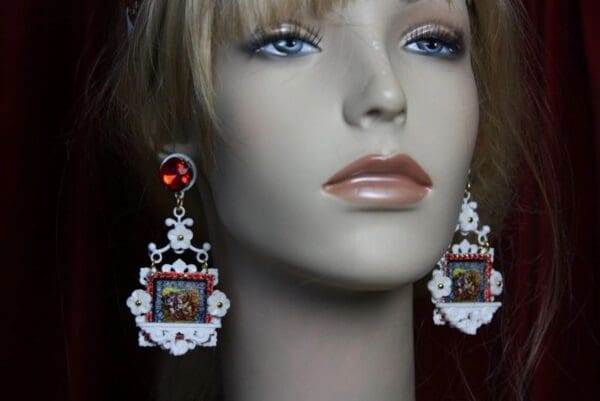 A mannequin wearing earrings with a picture of jesus.