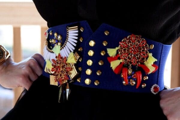 A person wearing a blue and red belt with gold accents.