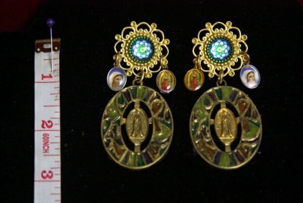 A pair of earrings with a virgin mary and other religious symbols.