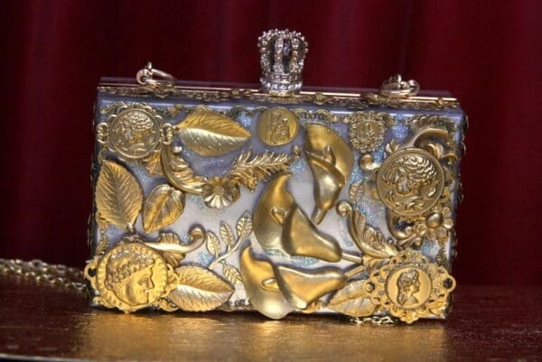 A silver and gold purse with some designs on it