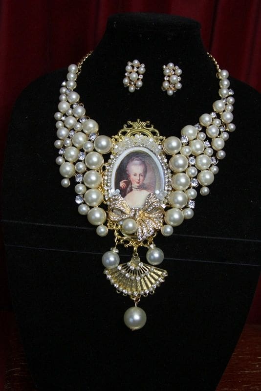 A necklace and earrings set with pearls, pearls and a picture of a woman.
