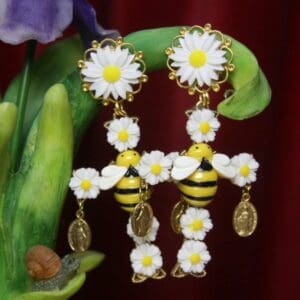 A pair of earrings with bees and daisies.