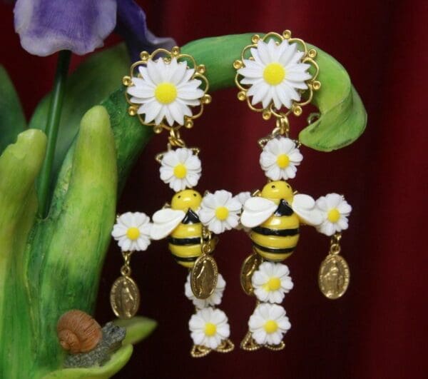 A pair of earrings with bees and daisies.