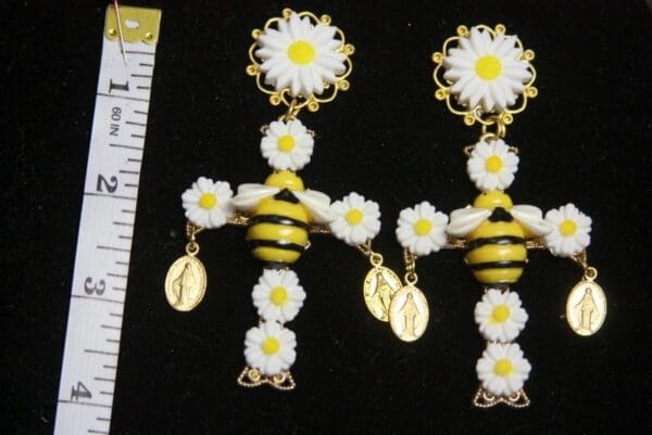 A pair of earrings with bees and daisies.