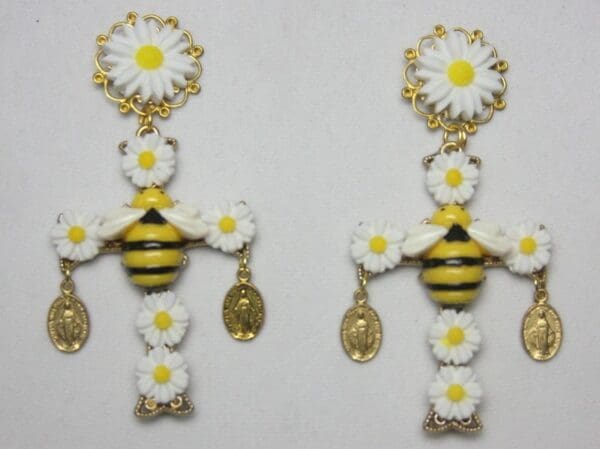A pair of earrings with bees and daisies.