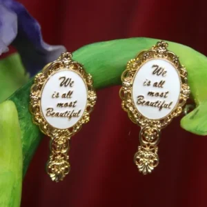 A pair of gold earrings with the words " we all most beautiful ".
