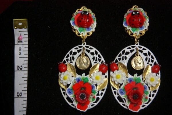 A pair of earrings with red flowers and white lace.
