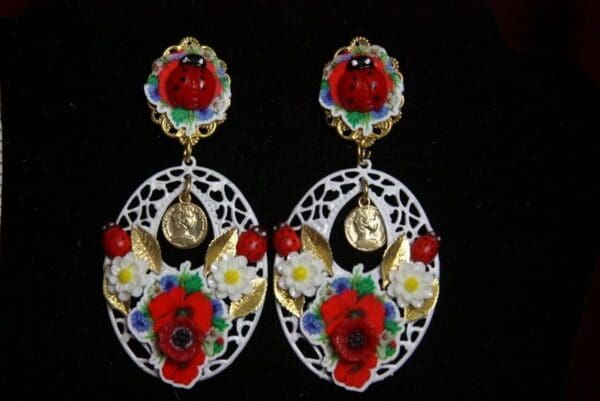 A pair of earrings with red flowers and gold accents.