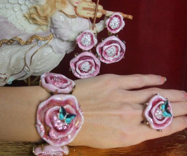 A woman 's hand wearing a pink bracelet and ring.