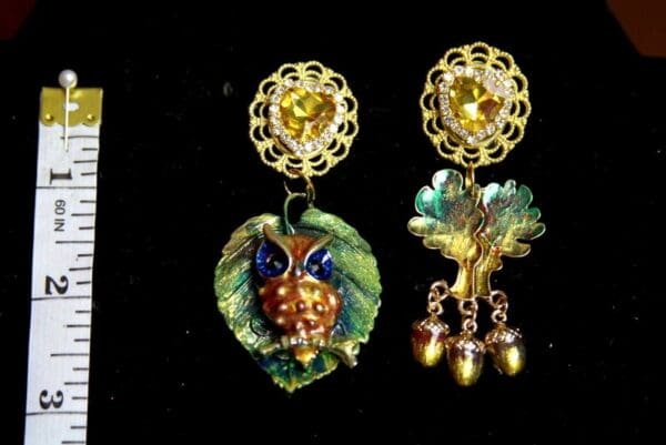 A pair of earrings with leaves and an owl.