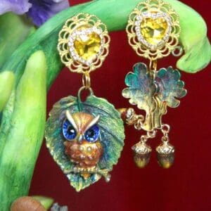 A pair of earrings with leaves and flowers on them.