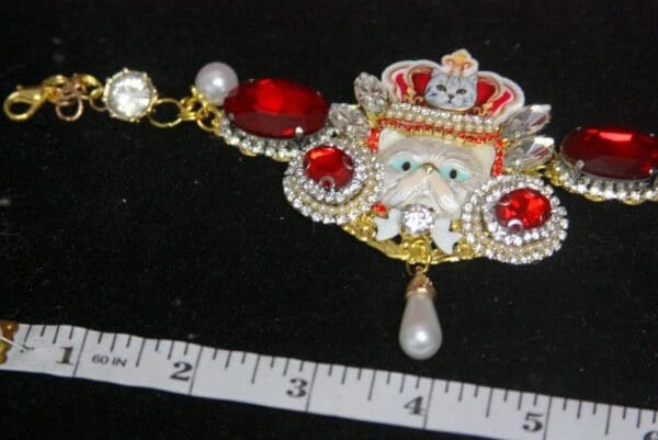 A red and white brooch with pearls on it