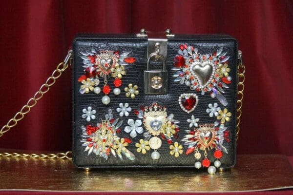 A black purse with flowers and hearts on it.