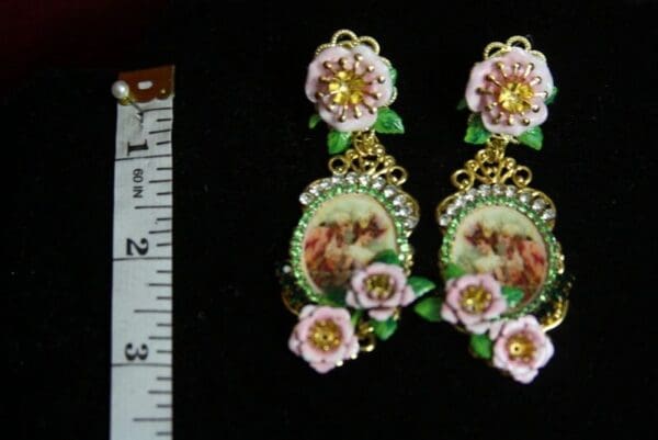 A pair of earrings with flowers and a picture.