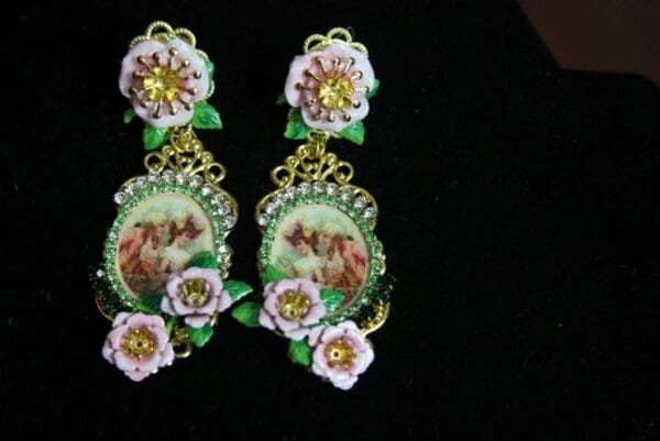 A pair of earrings with flowers and a picture.