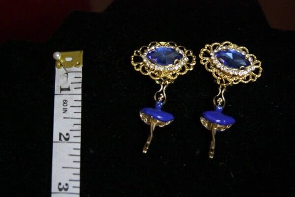 A pair of earrings with blue stones and gold filigree.