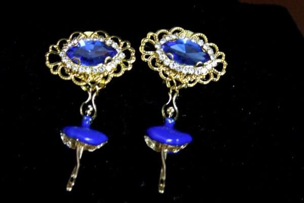 A pair of blue earrings with a ballerina on top.