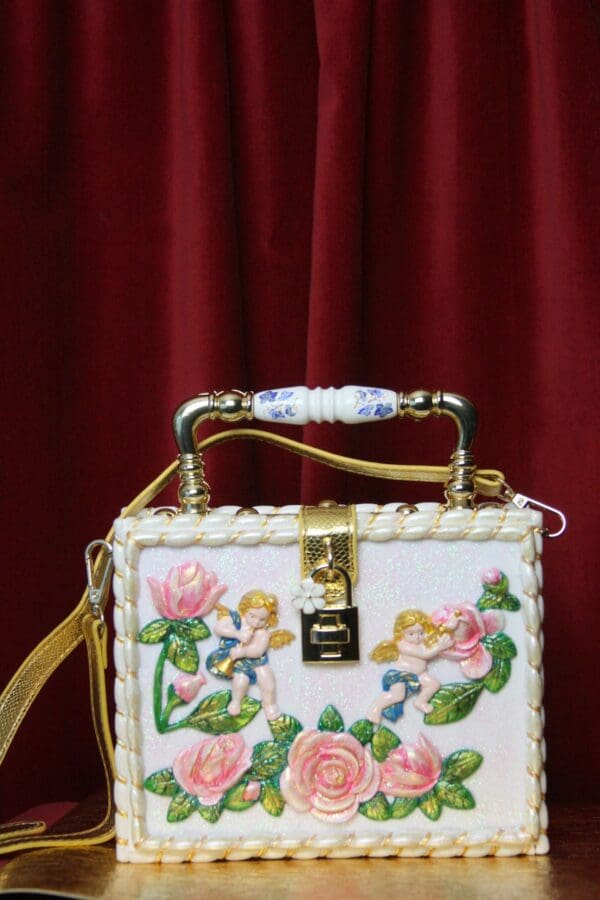 A white box bag with flowers and gold handle.