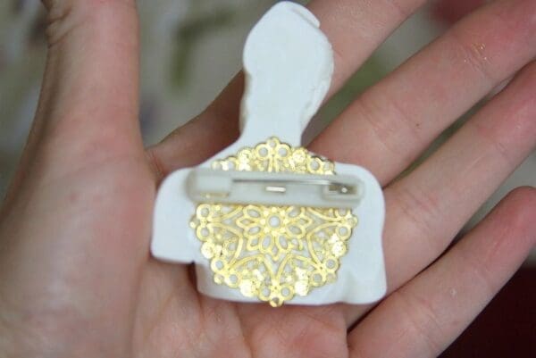 A person holding a white and gold pin