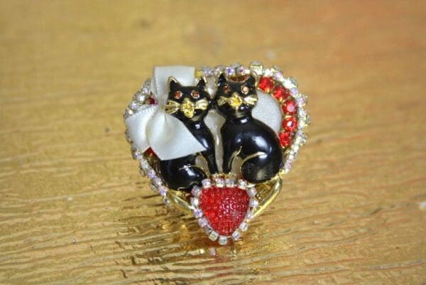 A heart shaped ring with two cats on it.