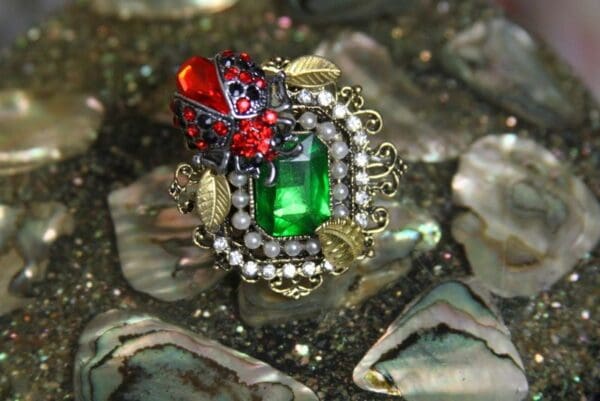 A green and red ring sitting on top of some rocks.