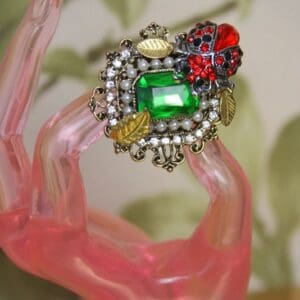 A green and red ring on top of a pink bracelet.