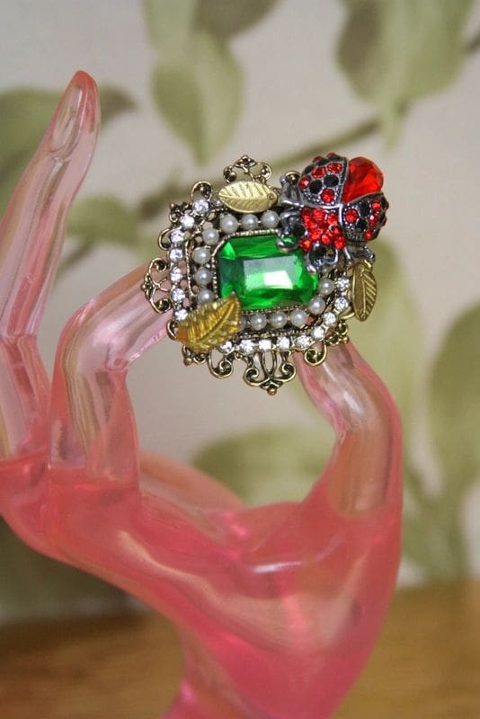 A green and red ring on top of a pink bracelet.