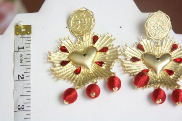 A pair of earrings with red beads and gold hearts.