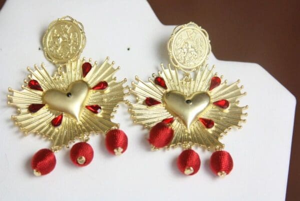 A pair of earrings with red and gold designs.