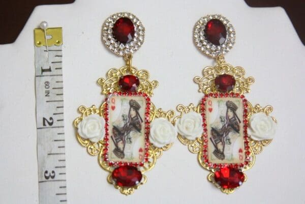 A pair of earrings with red stones and gold frame.