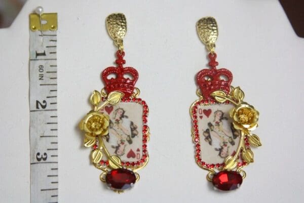A pair of earrings with red and gold decorations.