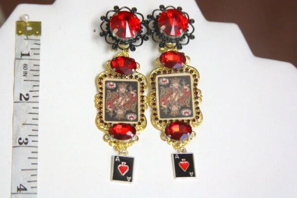 A pair of earrings with red stones and pictures.