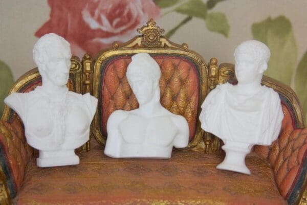 Three white busts are sitting on a table.