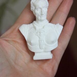 A white bust of a man in a hand.