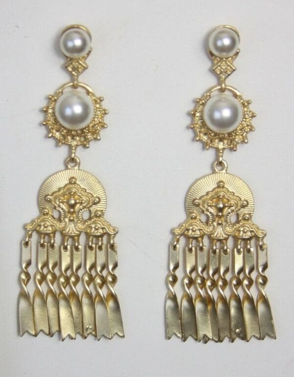 A pair of gold earrings with pearls hanging from them.