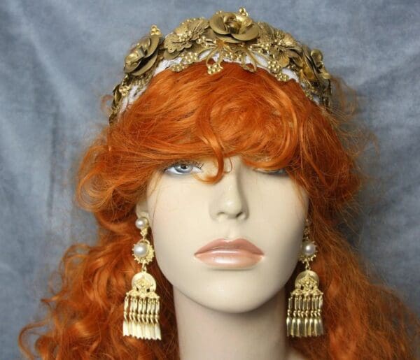 A woman with red hair wearing gold earrings and a crown.